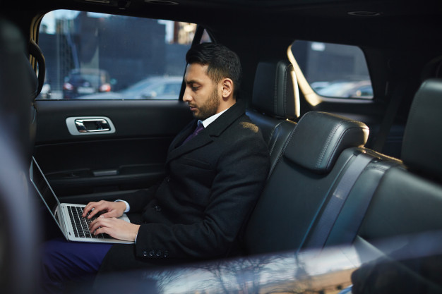 person using computer inside luxurious limousine